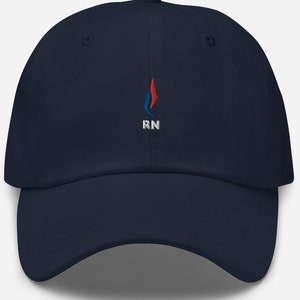 Peut inclure: Une casquette de baseball bleu marine avec un motif de flamme brodé en rouge, blanc et bleu et les lettres "RN" en blanc.