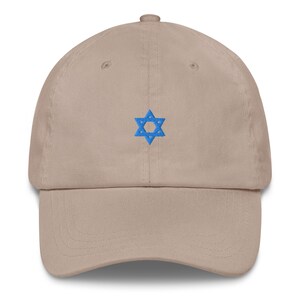 Könnte beinhalten: Beige Baseball Cap mit gebogenem Schirm. Auf der Vorderseite der Kappe ist ein blau gestickter Davidstern abgebildet. Der Hut besteht aus einem weichen Stoff und hat einen klassischen, lässigen Stil.