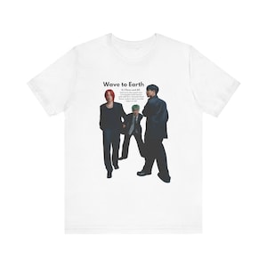 May include: White t-shirt featuring a graphic of three men in black suits. The text "Wave to Earth" is printed above the graphic. The text "Q.I. Flows and All..." is printed below the graphic.