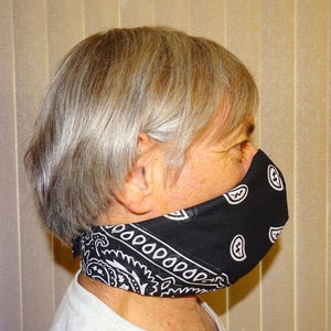 May include: A person wearing a black and white bandana face mask. The bandana is tied around the back of the head and the ends are tucked under the chin.