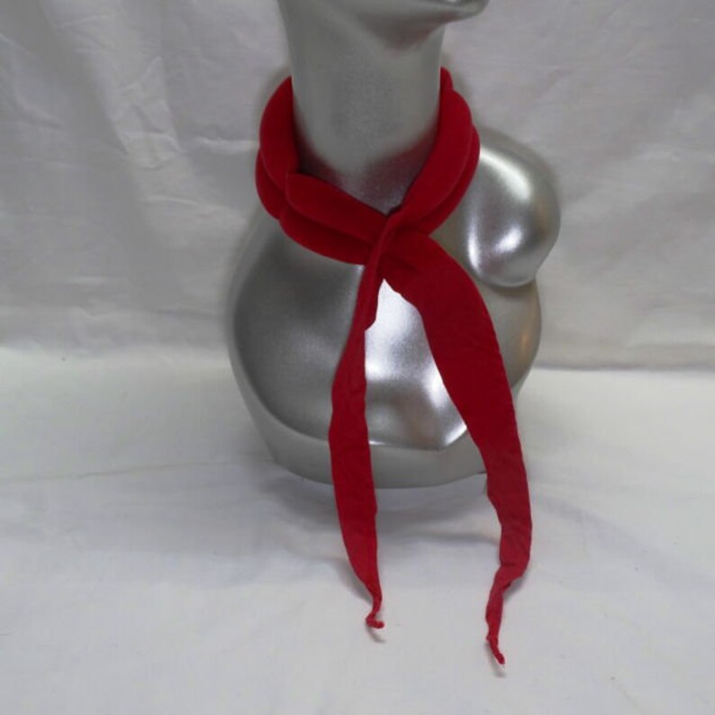 Puede incluir: Una bufanda roja brillante est&aacute; drapeada alrededor de un maniqu&iacute; plateado. La bufanda est&aacute; anudada en el cuello, con los extremos largos colgando. La tela parece suave y ligera, adecuada para climas c&aacute;lidos.