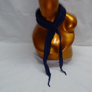 Puede incluir: Una bufanda azul marino est&aacute; drapeada alrededor de un maniqu&iacute; dorado. La bufanda est&aacute; hecha de un material suave y est&aacute; anudada en la parte delantera, con extremos largos y fluidos. El color oscuro de la bufanda contrasta con el tono dorado del maniqu&iacute;.