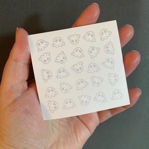 May include: A sheet of white paper with a repeating pattern of small, gray, cartoon dragon faces.