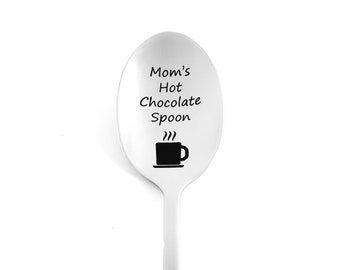 May include: A stainless steel spoon with the text "Mom's Hot Chocolate Spoon" and a graphic of a steaming mug. The spoon is designed for stirring hot chocolate and is a thoughtful gift.