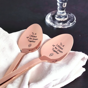 May include: Two rose gold spoons with the inscription "To A Lifetime of Ice Cream Together" and a small ice cream cone graphic.
