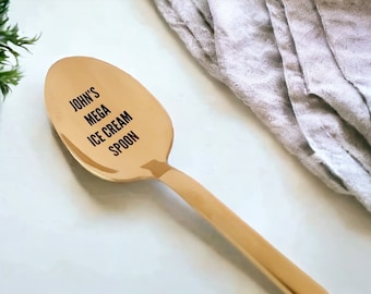 May include: A gold-colored ice cream spoon with the text "JOHN'S MEGA ICE CREAM SPOON" engraved on the front.