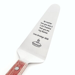 May include: A stainless steel pie server with a wooden handle. The blade has engraved text that reads "No matter how you slice it, I am thankful that you are my teacher. Love, Brooklyn 2020" with a pie graphic.