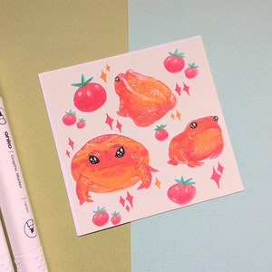 Pode incluir: Uma ilustração digital de três sapos laranja com olhos pretos e manchas brancas sobre um fundo bege claro com tomates vermelhos e estrelas brilhantes.