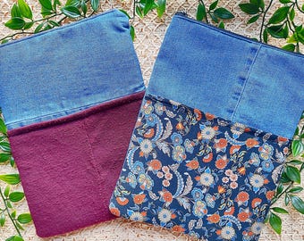 Könnte beinhalten: Zwei rechteckige Beutel. Einer ist aus blauem Denim und bordeauxfarbenem Stoff, der andere aus blauem Denim und marinefarbenem Stoff mit floralem Muster. Beide haben einen Reißverschluss. Sie liegen auf einer gewebten Oberfläche.