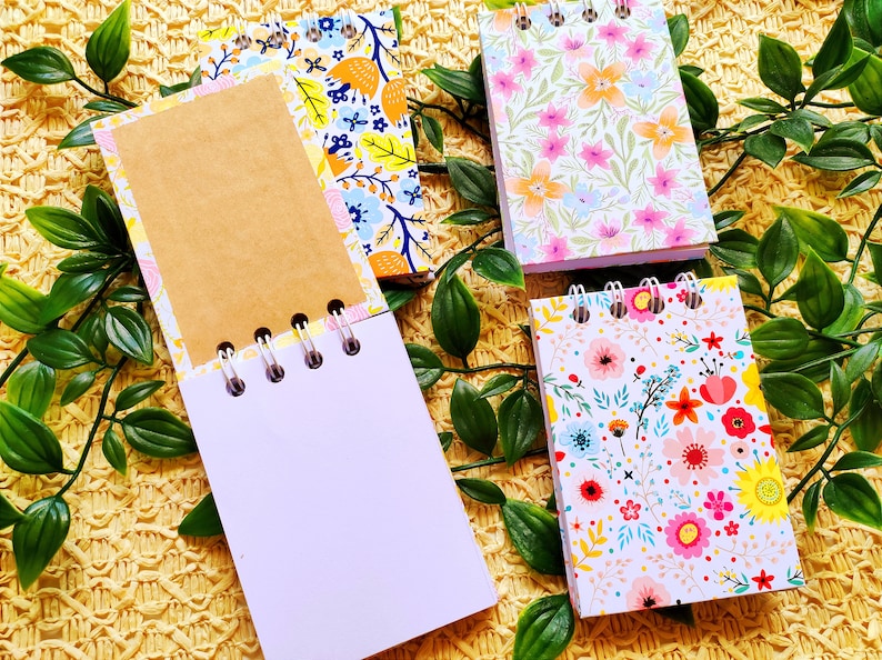May include: Four small spiral bound notebooks with floral patterns. The notebooks have white pages and are perfect for jotting down notes, ideas, or lists.
