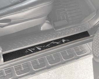 Puede incluir: Umbral de puerta de coche negro texturizado con un diseño de montaña gris. El umbral está elevado 1 mm y está fabricado por TUFSKINZ Manufacturing.