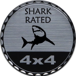 以下が含まれることがあります： 「SHARK RATED 4X4」という文字とサメのシルエットが描かれた、丸い銀と黒のステッカーです。
