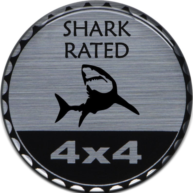 以下が含まれることがあります： 「SHARK RATED 4X4」という文字とサメのシルエットが描かれた、丸い銀と黒のステッカーです。