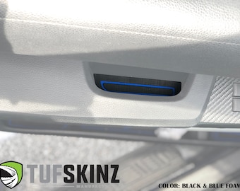 May include: Close-up of a black and blue foam car interior trim piece. The trim piece is installed on a car door panel and features a blue accent line. The text "TUFSKINZ MANUFACTURING" is visible in the bottom right corner of the image.
