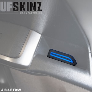 May include: Close-up of a car's interior door panel with a black and blue foam insert. The insert has a blue stripe running along the centre. The text "COLOR: BLACK & BLUE FOAM" is visible at the bottom of the image.