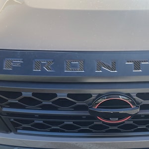 Tufskinz |  Letter-inzetstukken in grille: past op Nissan Frontier 2022-2025: verschillende sets
