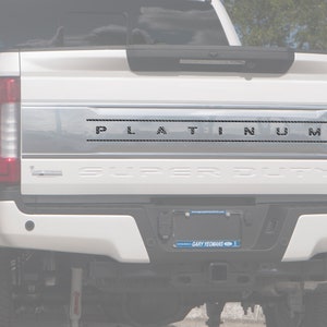 Puede incluir: Camioneta blanca con una puerta trasera cromada y la palabra "PLATINUM" en relieve en negro en la puerta trasera.