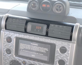 Puede incluir: Un kit de moldura de tablero de fibra de carbono negro para un automóvil. El kit incluye una moldura de consola central, una moldura de tablero y una moldura de ventilación. El kit está diseñado para darle a tu automóvil un aspecto deportivo y elegante. El kit está hecho de fibra de carbono de alta calidad y es fácil de instalar. El kit viene con un mensaje de advertencia que dice: "Operar este producto mientras conduce puede ser una distracción o peligroso si no se hace con cuidado. Al operar este producto, la prioridad del conductor debe ser concentrarse en obedecer todas las reglas de tráfico. Usted asume todos los riesgos relacionados con el uso de este producto. Eliminar automáticamente este mensaje después de 10 segundos. Aceptar."