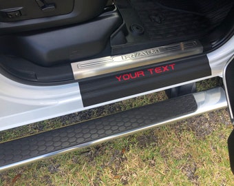 May include: Black and silver car door sill with a red "RAM" logo and the text "YOUR TEXT" on a black background.