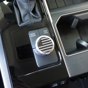 May include: A black and white American flag design on a silver knob with the words "Drive Mode" and "Tow Haul" on a black panel.