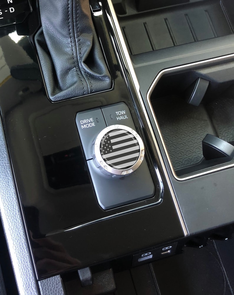 May include: A black and white American flag design on a silver knob with the words "Drive Mode" and "Tow Haul" on a black panel.