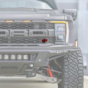 Puede incluir: Vista frontal de una camioneta gris con una parrilla negra de panal con luces de posición ámbar, un logotipo de Ford prominente y un pequeño emblema FP rojo y negro. El vehículo incluye un parachoques de acero resistente con luces LED.
