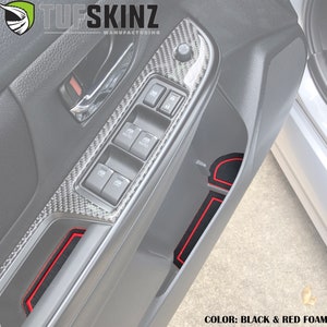 May include: Black and red foam door liner inserts with a red trim. The liner inserts are designed to fit in the door pockets of a car. The image shows the liner inserts installed in a car door. The door has a carbon fibre pattern and window controls. The text "COLOR: BLACK & RED FOAM" is visible at the bottom of the image.