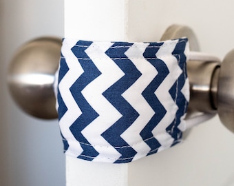 May include: A white door with a silver door knob. A blue and white chevron patterned fabric doorstop is wrapped around the door knob.