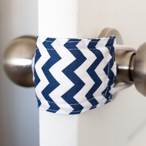 Könnte beinhalten: Eine weiße Tür mit einem blauen und weißen Zickzack-Stoff-Türstopper, der um den Türknauf gewickelt ist.