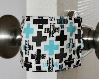 May include: A white door with a silver door knob. A fabric doorstop with a black and blue geometric pattern is wrapped around the door knob.