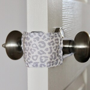Puede incluir: Primer plano de un pomo de puerta con una tela de estampado de leopardo envuelta alrededor. La tela est&aacute; asegurada con un trozo de cuerda.