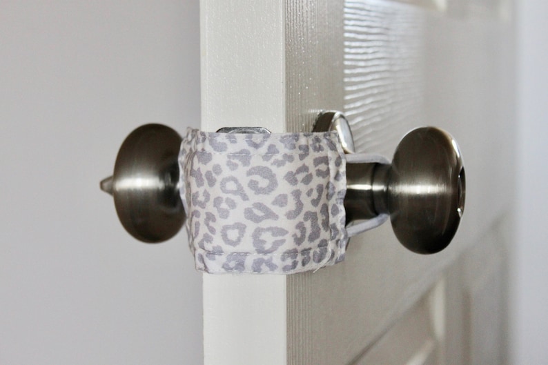 Puede incluir: Primer plano de un pomo de puerta con una tela de estampado de leopardo envuelta alrededor. La tela est&aacute; asegurada con un trozo de cuerda.