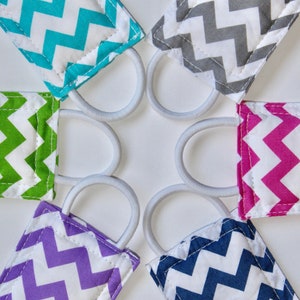Puede incluir: Seis gomas para el pelo de tela de colores con un patr&oacute;n de chevron en turquesa, verde, rosa, morado, azul marino y gris. Las gomas para el pelo est&aacute;n dispuestas en c&iacute;rculo sobre un fondo blanco.