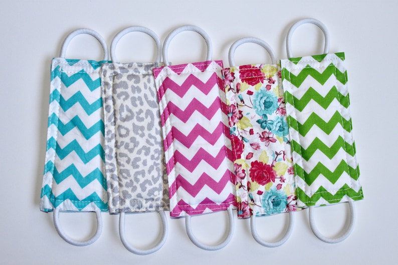 Puede incluir: Cinco tapones de puerta cubiertos de tela con lazos el&aacute;sticos blancos. Los tapones de puerta son de varios patrones, incluyendo chevron turquesa y blanco, estampado de leopardo gris y blanco, chevron rosa y blanco, floral y chevron verde y blanco.