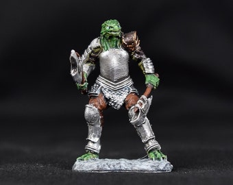 May include: A green and silver painted miniature figurine of a humanoid creature wearing armour and holding a weapon. The figurine is standing on a grey base.