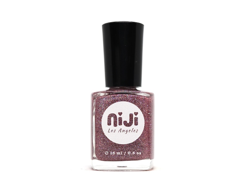 Puede incluir: Una botella de vidrio transparente de esmalte de u&ntilde;as con una tapa negra. La botella est&aacute; llena de un esmalte de u&ntilde;as con purpurina rosa y morado brillante. La etiqueta de la botella dice "niji Los Angeles" y "16 ml / 0.5 oz."
