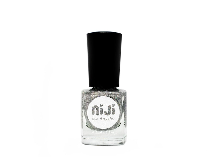 May include: A silver glitter nail polish bottle with a black cap. The bottle has a white label with the text "niji Los Angeles" and a small heart design.