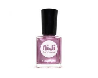 Puede incluir: Una botella de esmalte de uñas metálico rosa con una etiqueta circular blanca que dice "niji Los Angeles" con dos pequeños corazones a cada lado de la palabra "niji".