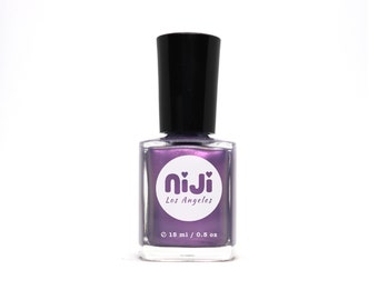 Puede incluir: Una botella de esmalte de uñas morado con un brillo plateado. La botella está etiquetada como "niji Los Angeles" y tiene un círculo blanco con dos corazones alrededor del texto. La botella es de 0,5 oz o 15 ml.