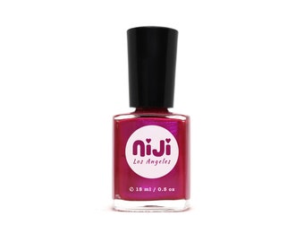 Puede incluir: Una botella de esmalte de uñas rosa con acabado holográfico. La botella está etiquetada como "niji Los Angeles" y tiene un círculo blanco con un corazón rosa en el centro. La botella contiene 15 ml de esmalte.
