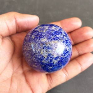 May include: A smooth, round, blue and white lapis lazuli sphere with gold flecks.