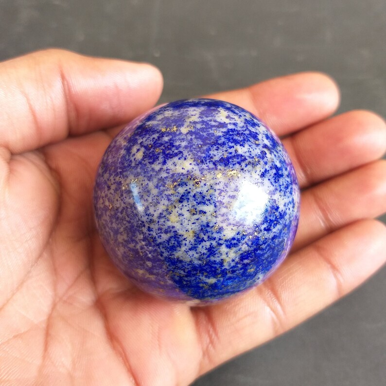 May include: A smooth, round, blue and white lapis lazuli sphere with gold flecks.