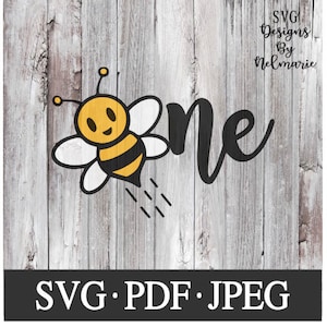 Puede incluir: Una abeja de dibujos animados negra y amarilla con una cara sonriente vuela junto a la palabra "uno" en escritura negra. La imagen está sobre un fondo de veta de madera con el texto "SVG Designs by Nelmarie" y "SVG. PDF. JPEG" en la parte superior e inferior de la imagen.