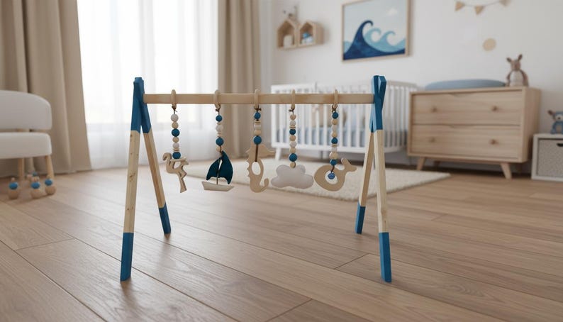 May include: Wooden baby play gym with blue accents and hanging toys. The toys include a sailboat, cloud, and whale. The gym is set up in a nursery with a crib and dresser in the background.