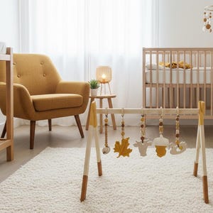 May include: A nursery scene with a wooden baby play gym featuring hanging toys, a crib, and a mustard-colored armchair. The room has a neutral color palette with a white rug and curtains.