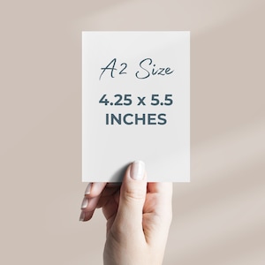 May include: A white card with the text "A2 Size 4.25 x 5.5 INCHES" written in black. A hand is holding the card.