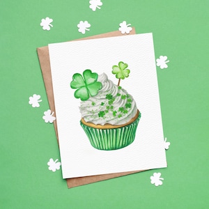 May include: A white cupcake with green frosting and a shamrock on top. The cupcake is decorated with green sprinkles and a small shamrock.