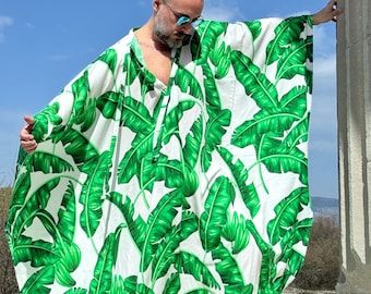May include: A white and green kaftan with a banana leaf print. The kaftan is loose fitting and has a long, flowing silhouette.