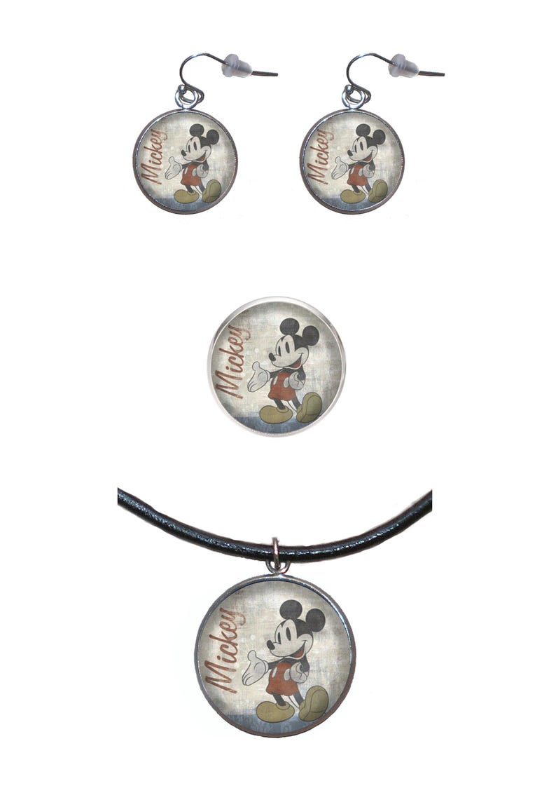 May include: A set of Mickey Mouse jewelry featuring a necklace, earrings, and a brooch. The necklace has a black leather cord and a round pendant with a vintage image of Mickey Mouse. The earrings are silver with round pendants featuring a vintage image of Mickey Mouse. The brooch is a round silver pin with a vintage image of Mickey Mouse.