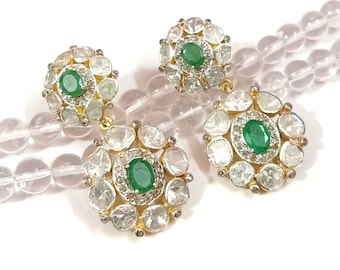 Puede incluir: Un par de pendientes de oro con piedras preciosas verdes y diamantes blancos engastados en un diseño circular. Los pendientes se muestran en una hebra de cuentas transparentes.